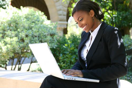 A female MBA student working on her laptop in the park.